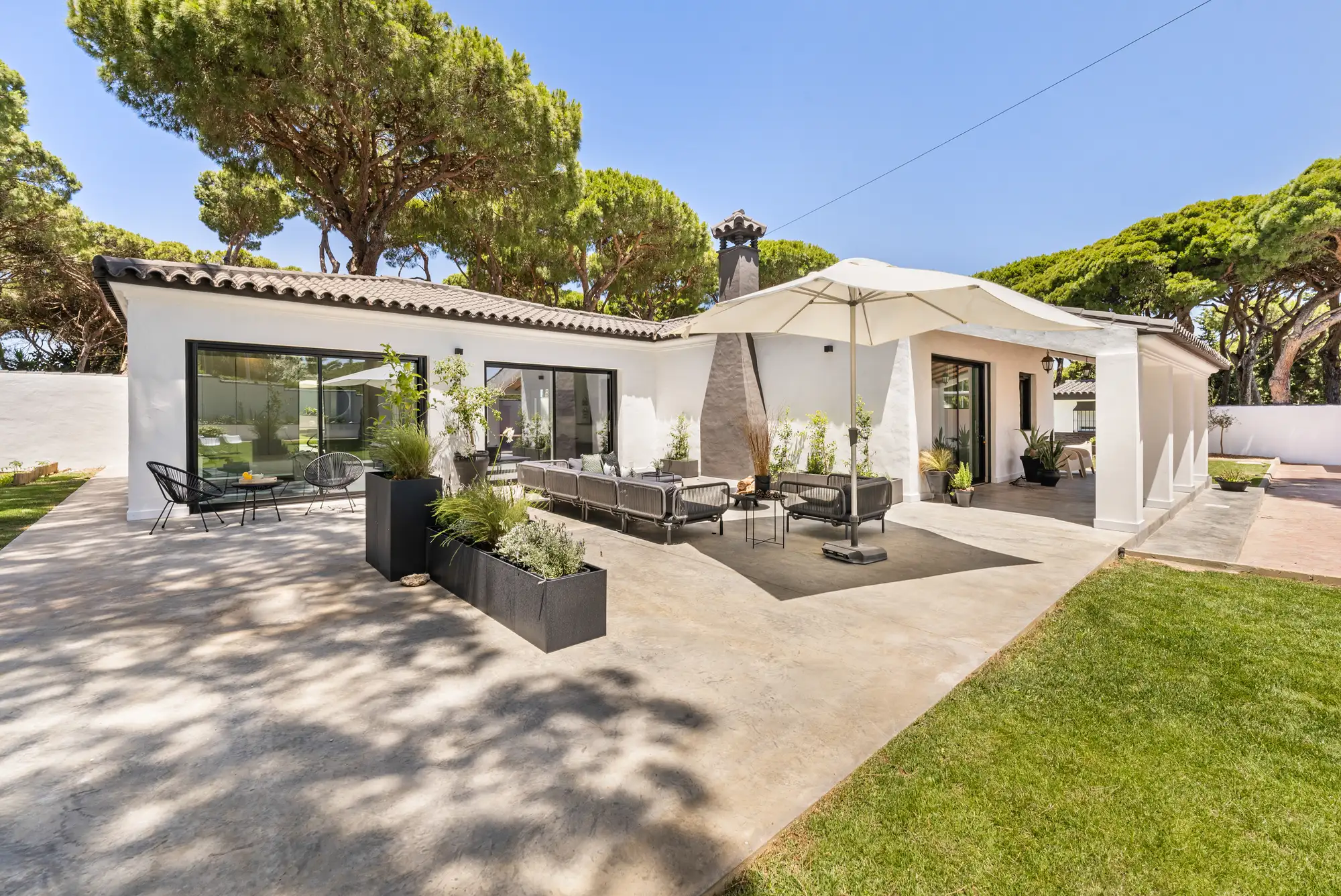 Überdachte Terrasse mit Outdoor-Lounge und Sonnenschirm